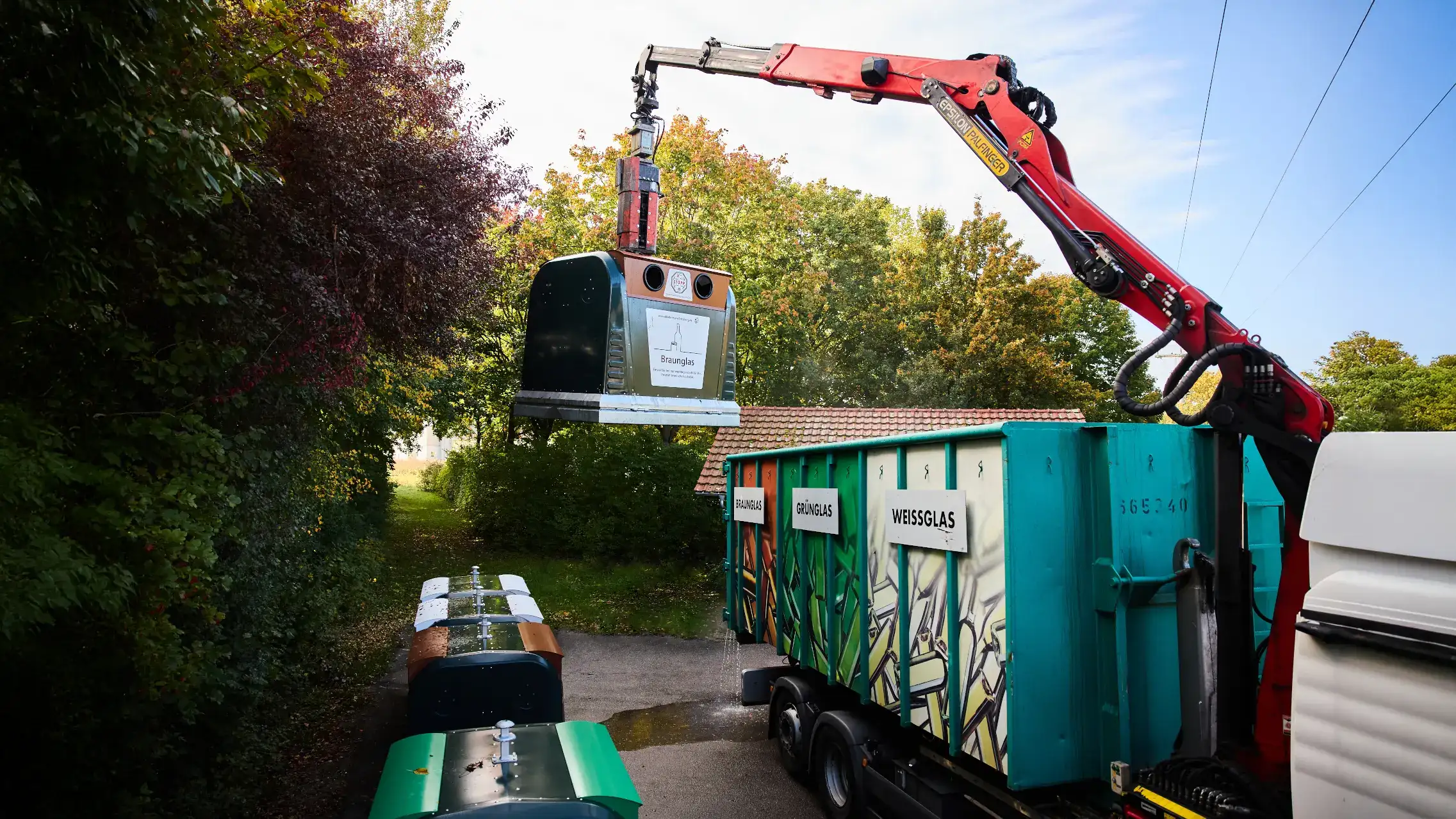 A glass-recycling container that is being emptied A glass-recycling container that is being emptied