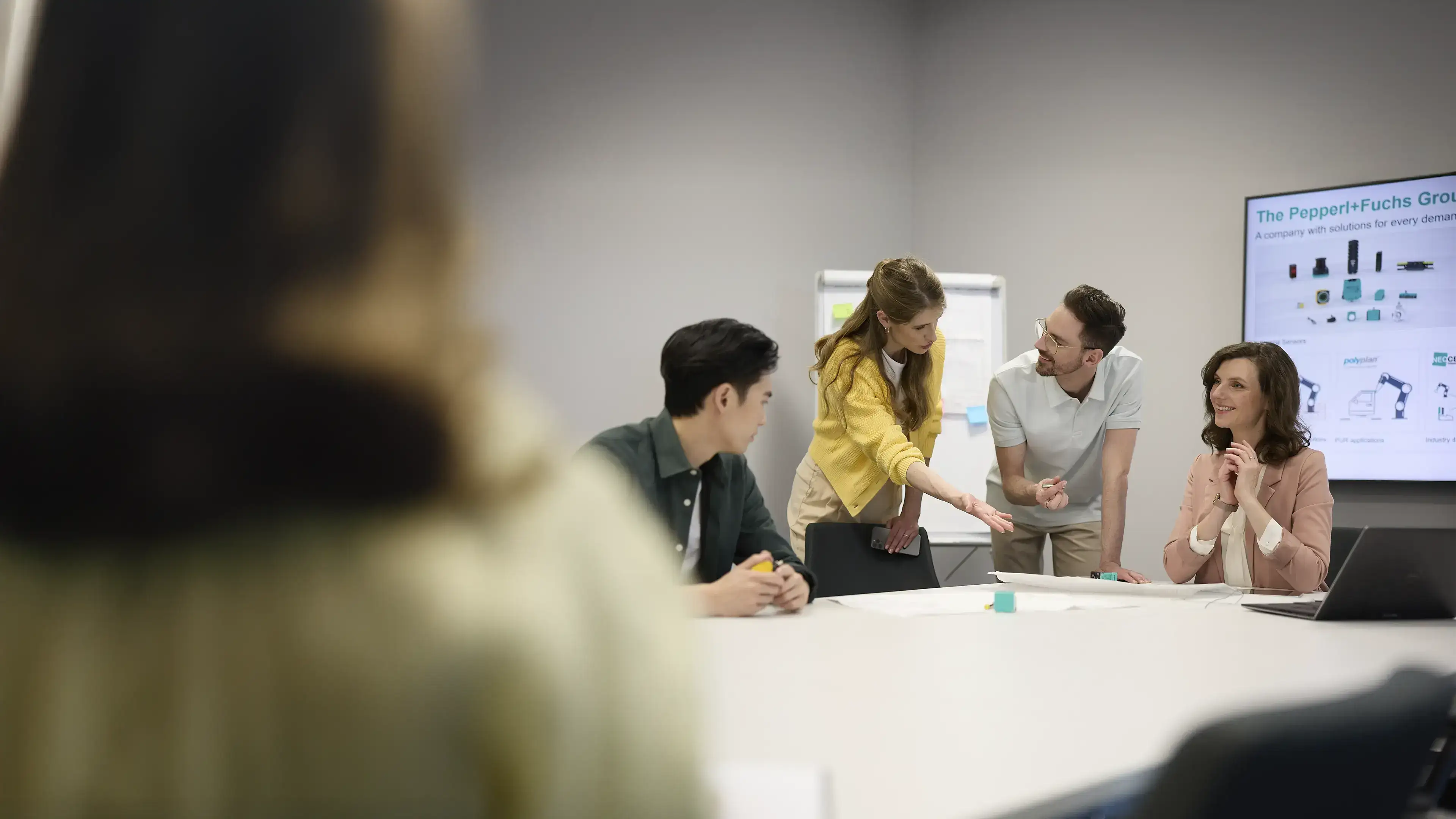 four people sitting at a table and discussing products and solutions